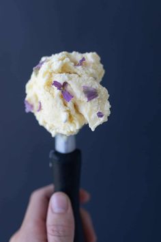 a hand holding an ice cream cone with purple flowers on it