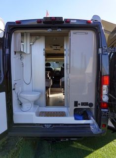 an open van door on the back of a white vehicle with its doors opened and toilet in it