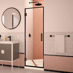 a bathroom with pink tiles and black trim around the shower stall, sink and mirror