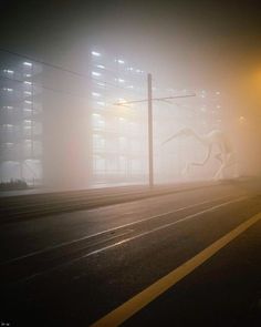 a foggy street at night with an animal statue in the foreground