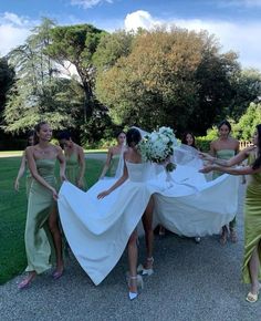 a group of bridesmaids in green dresses are pulling the bride's dress