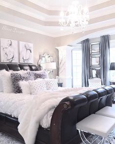 a bedroom with a bed, chandelier and pictures on the wall above it