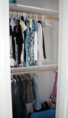 an open closet with clothes hanging on wooden shelves and blue trash can in the foreground