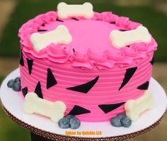 a pink cake with black and white designs on it's sides, topped with a dog bone