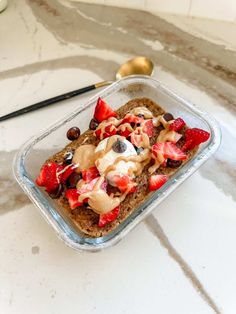 a glass dish filled with granola, fruit and yogurt on top of a counter