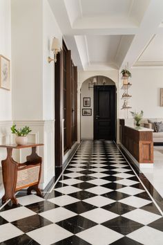 a hallway with black and white checkered flooring next to a wooden door on the wall