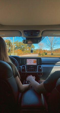 two people sitting in the back seat of a car with their hands on the steering wheel