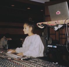 a woman sitting in front of a laptop computer on top of a sound mixing desk