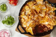 a casserole dish with tortilla shells, tomatoes, and green onions