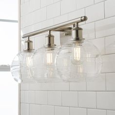 three lights are hanging on the wall in front of a white tiled wall and window