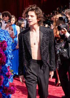 a man in a black suit walking down a red carpet