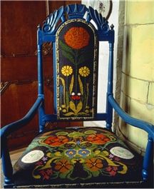 an ornately decorated chair sitting in front of a brick wall and wooden paneled door