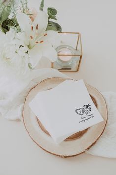 napkins on a plate next to flowers and a box with a candle in it