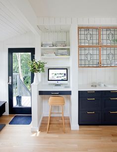 a desk with a computer on top of it in front of a door and window