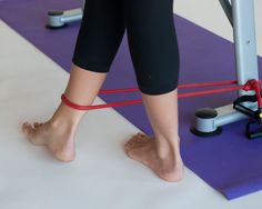 a woman standing on a mat with her feet propped up in the air while using an exercise machine