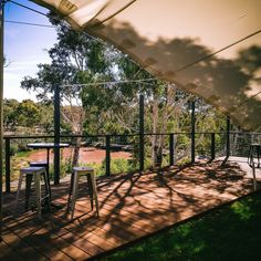 an outdoor patio with tables and chairs under a tented area that overlooks a river