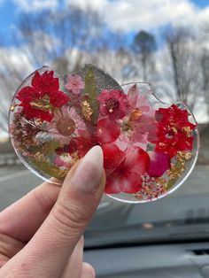 a person holding up a sticker with flowers on it in front of a car