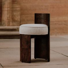 a wooden chair with a white cushion sitting on top of it's back end