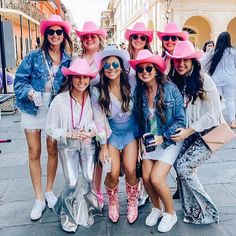 a group of women wearing pink hats and sunglasses posing for a photo on the street