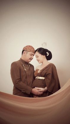 a man and woman standing next to each other in front of a white wall,