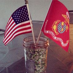 two flags sticking out of a mason jar filled with nuts and beans on a table