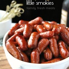 a white bowl filled with hot dogs on top of a wooden table