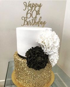 a white and gold birthday cake with flowers on top