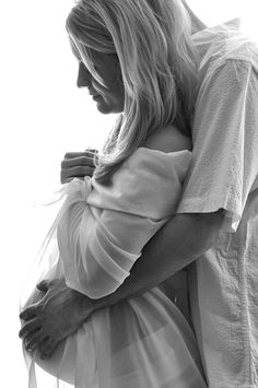 black and white photograph of a woman holding a baby in her arms while she is wearing a dress