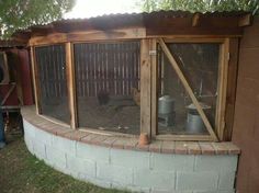 a chicken coop built into the side of a brick building with a large window on top