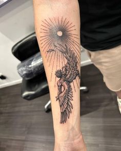 a person with a bird tattoo on their arm and the sun above them is shining