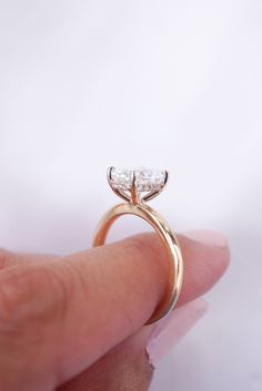 a woman's hand holding an engagement ring with two pear shaped diamonds on it