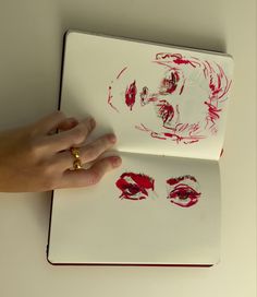 a person's hand on top of a white laptop with red ink and the image of a woman's face