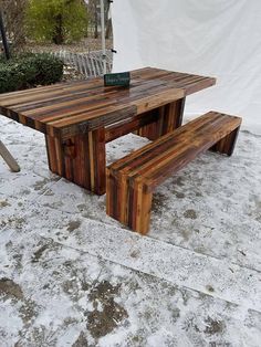 a wooden table and bench sitting in the snow