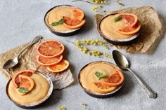 three small bowls filled with oranges and some silverware on top of a table