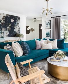 a living room filled with blue couches and pillows on top of a rug next to a coffee table