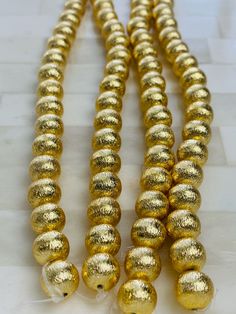 some gold colored beads are on a white table and there is no image to describe