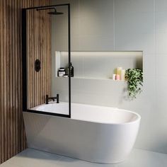 a white bath tub sitting in a bathroom next to a wooden shower door and wall