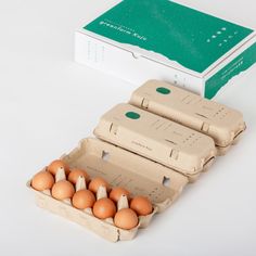 an egg carton with six eggs in it next to a box of brown eggs