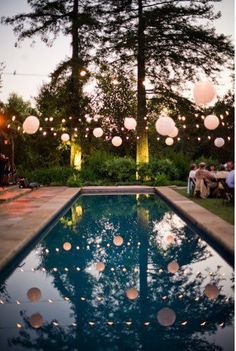 some paper lanterns are hanging over the pool