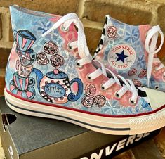 Custom hand painted Converse Chuck Taylors for your daughters Bat Mitzvah complete with her theme and option to have crystals added. Happy to present another new design from my studio. But this is just a sampling of what I can customize for you. This clients daughter loves Alice in Wonderland but wanted the shoes to match her chiffon blue dress with some pinks. Teacup and Teapots with chiffon lace and checkerboard in black and white. I will work with you for the perfect design for your daughters Hand Painted Converse High Tops, Alice In Wonderland Converse, Converse For Girls, Painted Converse High Tops, Custom Painted Converse, Hand Painted Converse, Alice In Wonderland Shoes, Canvas Shoes Diy, Painted Converse