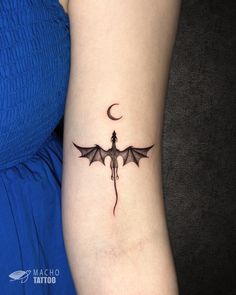 a woman's arm with a tattoo on it that is shaped like a bat