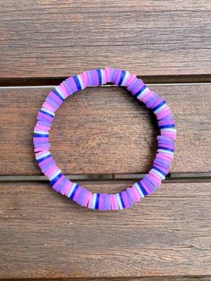 a purple and blue bracelet sitting on top of a wooden bench