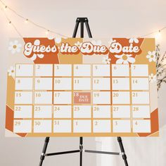 a calendar on a tripod stands in front of a white wall with string lights