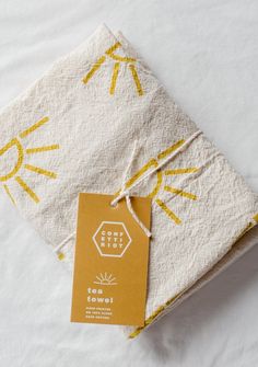 two napkins with yellow and white designs on them, one has a tag attached to it