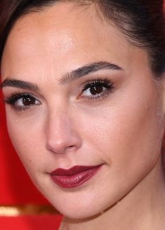 a close up of a woman with dark hair and red lipstick on her face, looking at the camera