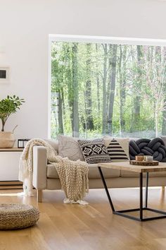 a living room filled with furniture and a large window covered in lots of natural light