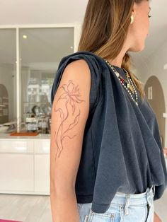 a woman with a flower tattoo on her arm and shoulder, standing in front of a kitchen