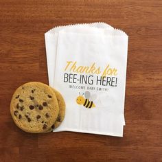 there is a bag with a cookie on it next to a chocolate chip cookie that says thanks for bee - ing here