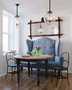 a blue chair and table in a room with wooden floors, two mirrors on the wall