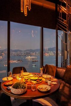 a dining room table with food on it and large windows looking out at the water